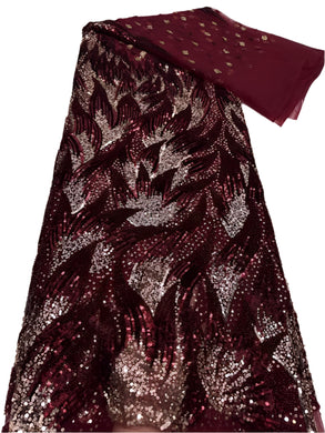 Sequined fabric with a leaf pattern in red and gold on a white surface